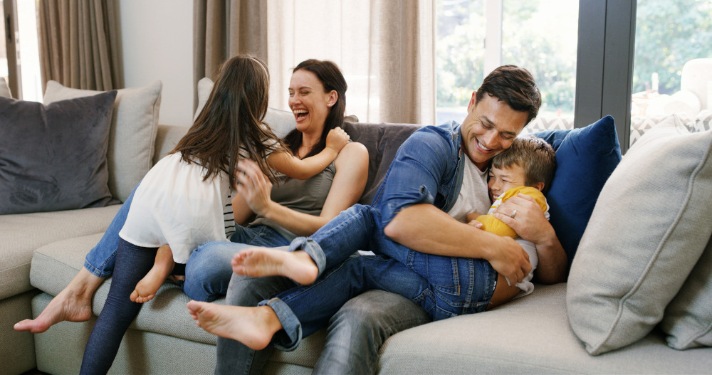parents hugging their kids on the couch in their home